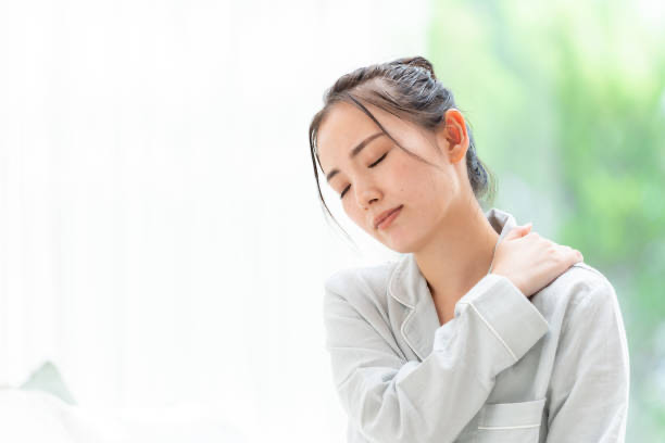 肩に手を当てて痛そうな表情をしている女性